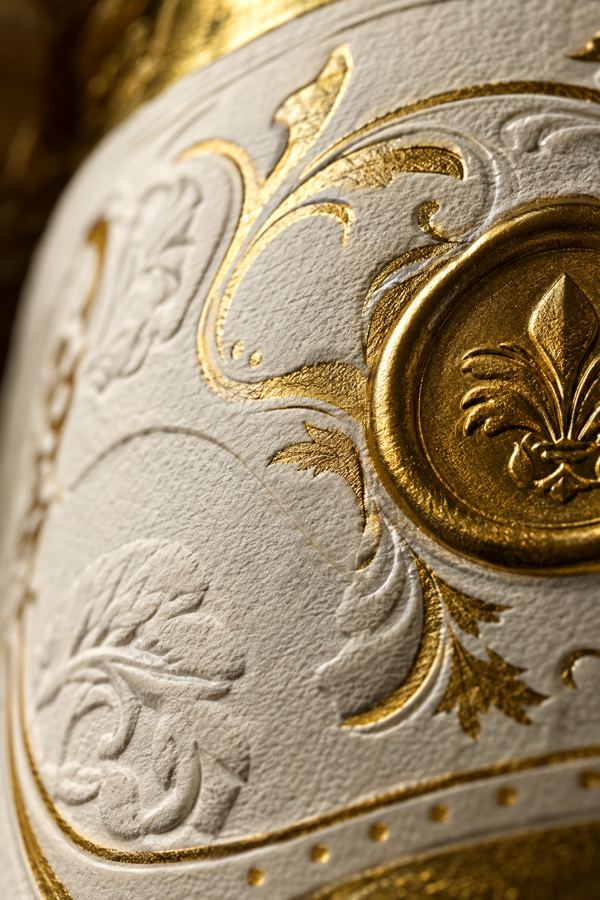 Close-up of a cream spirits label with deep embossing, gold foil filigree, and a gold medallion